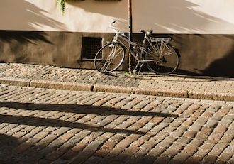 black city bike parked beside white concrete wall